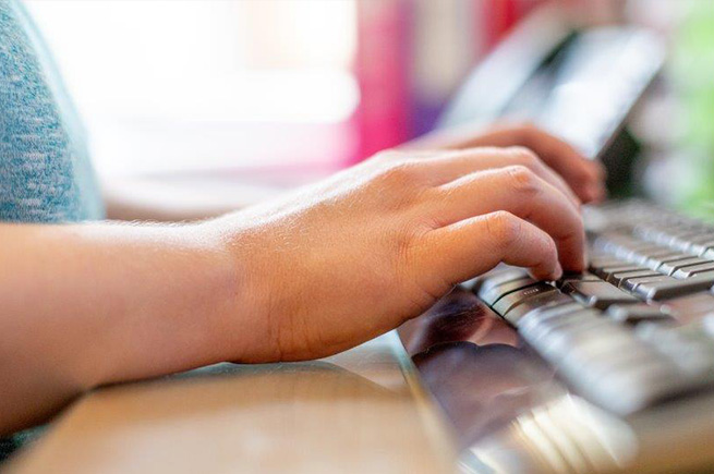 A woman's hands typing on a computer keyboard